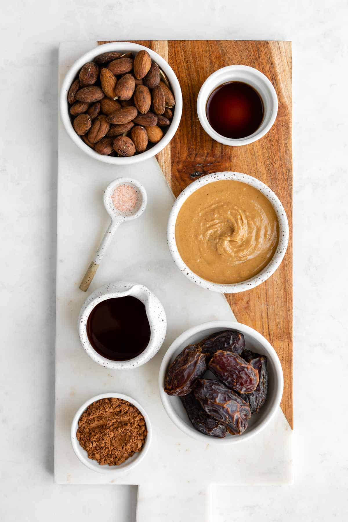 a marble serving board topped with bowls of coffee soaked almonds, medjool dates, almond butter, maple syrup, cocoa powder, vanilla extract, and salt