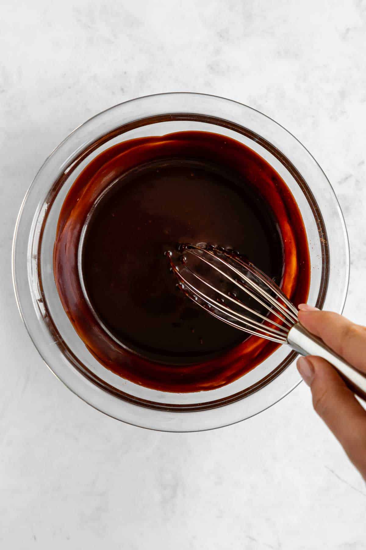 whisking chocolate ganache in a glass bowl