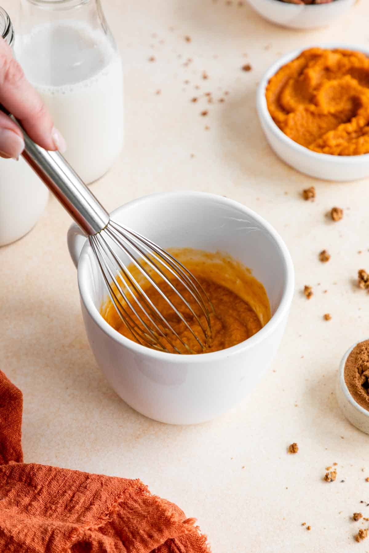 whisking pumpkin cake batter in a mug