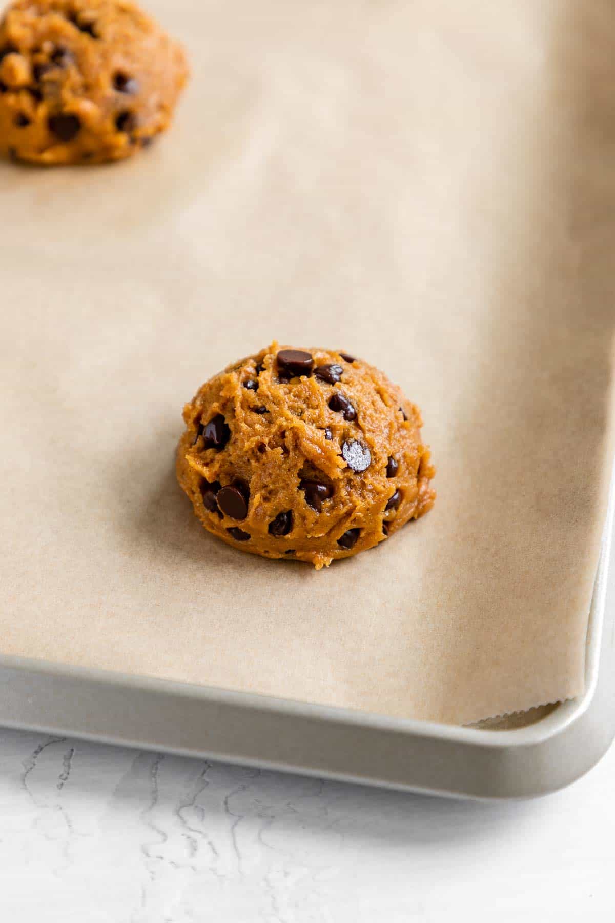 a round of vegan pumpkin chocolate chip cookie dough on a baking sheet