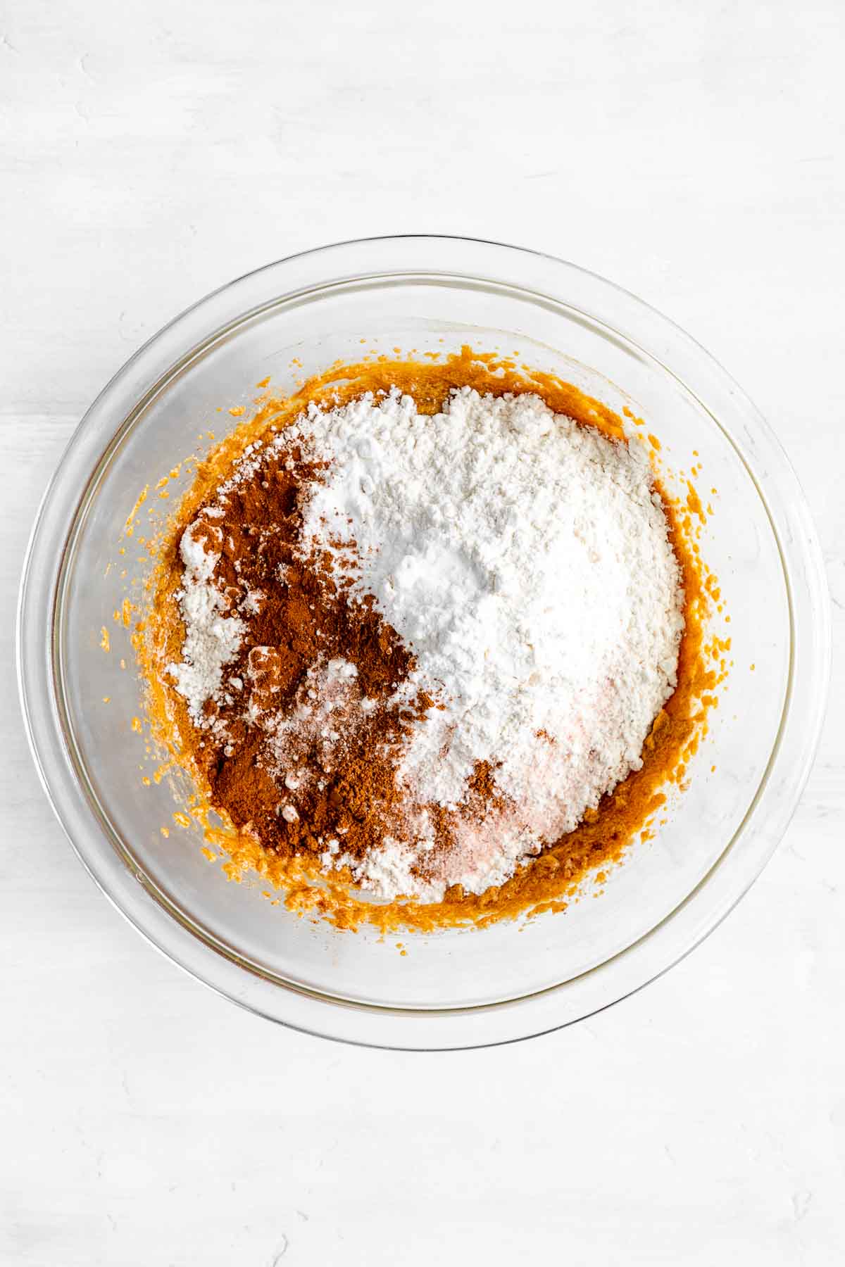 flour, cinnamon, pumpkin pie spice, and salt on top of creamed butter and sugar inside a glass bowl