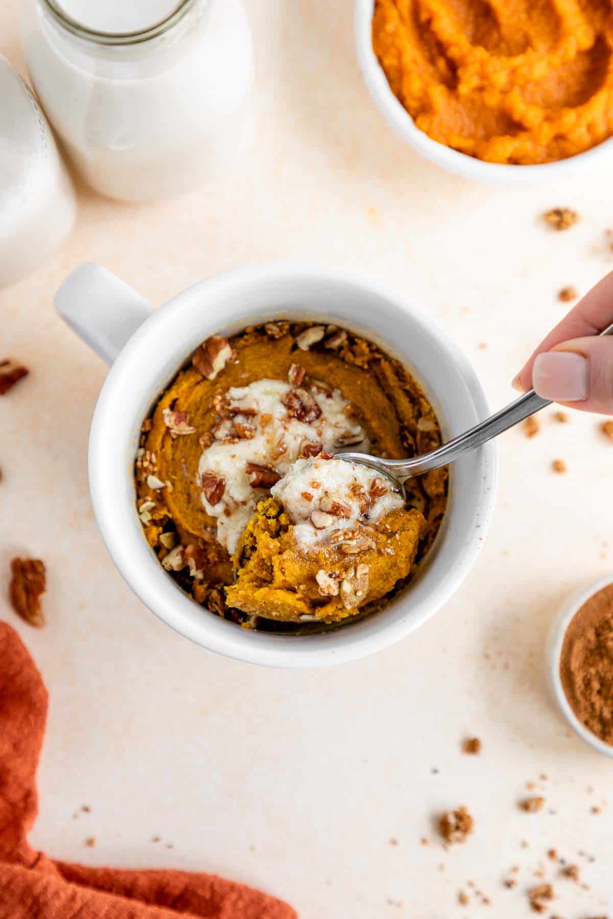 scooping a spoon into a vegan pumpkin mug cake