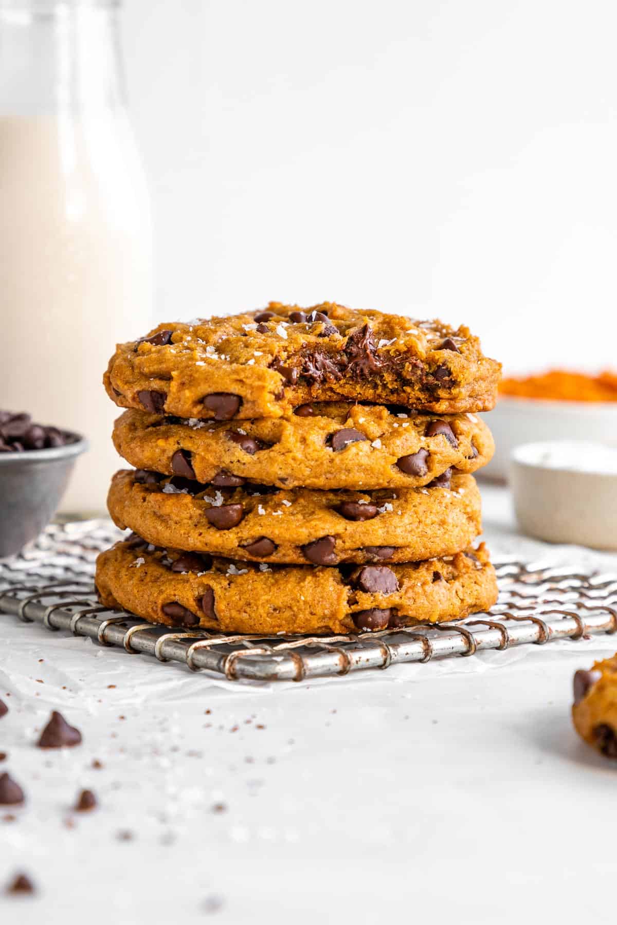 a stack of vegan pumpkin chocolate chip cookies with a bite taken out of the top cookie