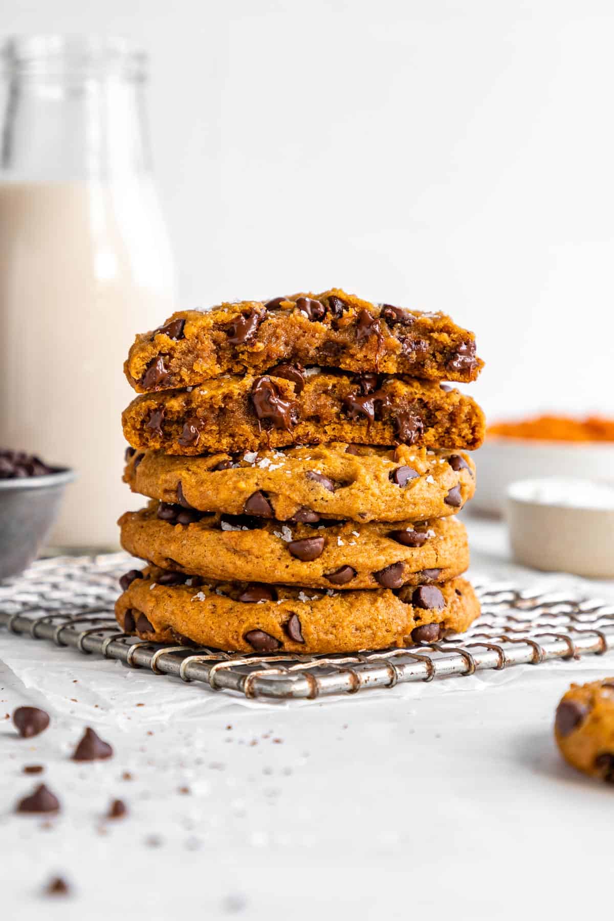 vegan pumpkin chocolate chip cookies stacked on top of each other with the top two cookies sliced in half