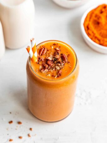 vegan pumpkin pie smoothie in a glass with granola and pecans