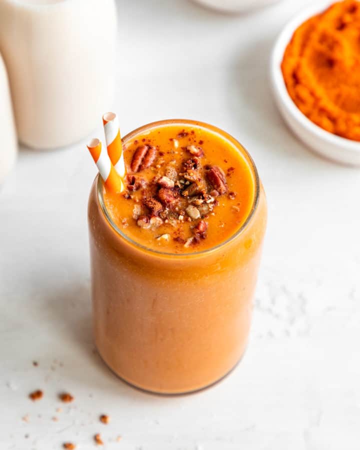 vegan pumpkin pie smoothie in a glass with granola and pecans