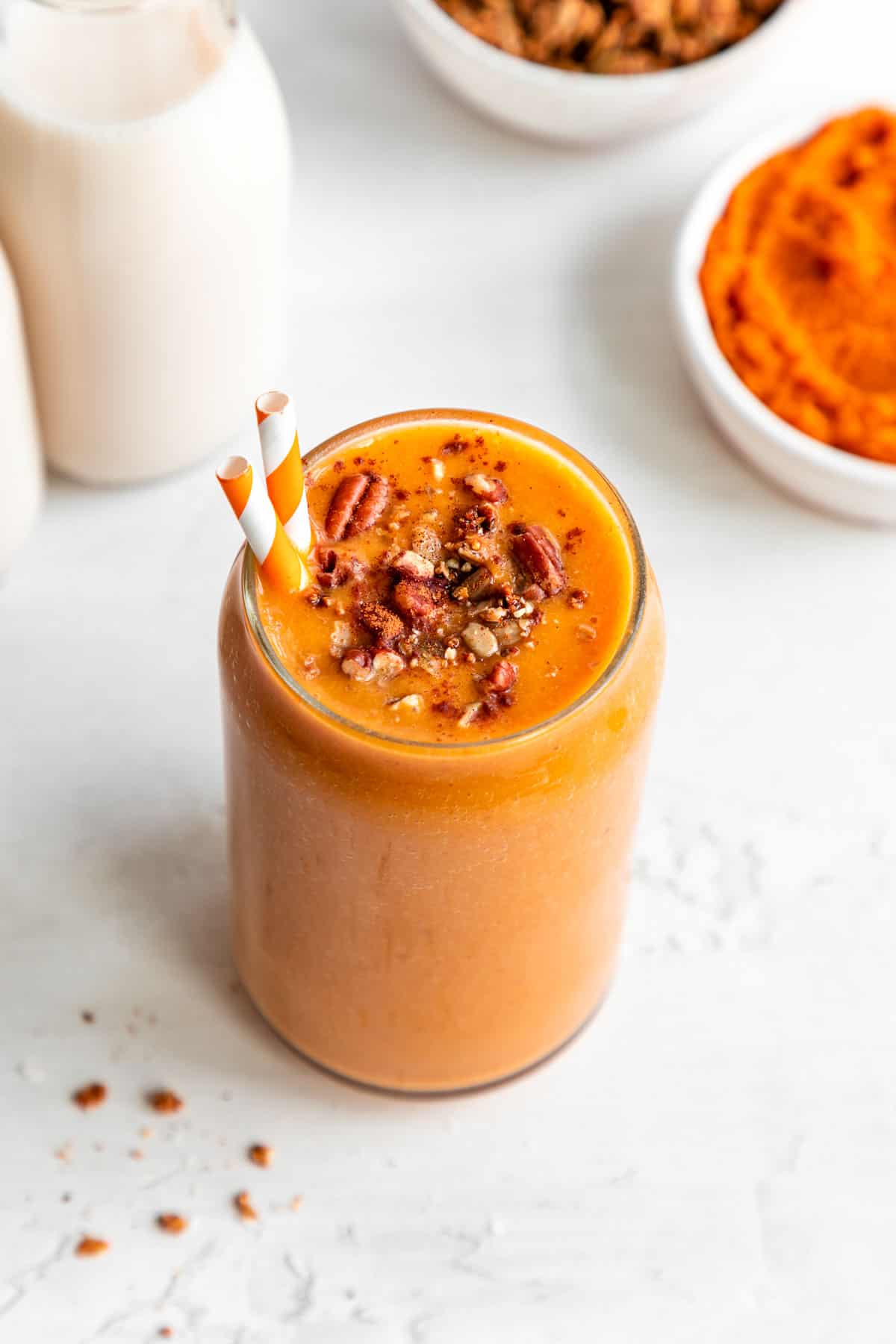 vegan pumpkin pie smoothie in a glass with granola and pecans