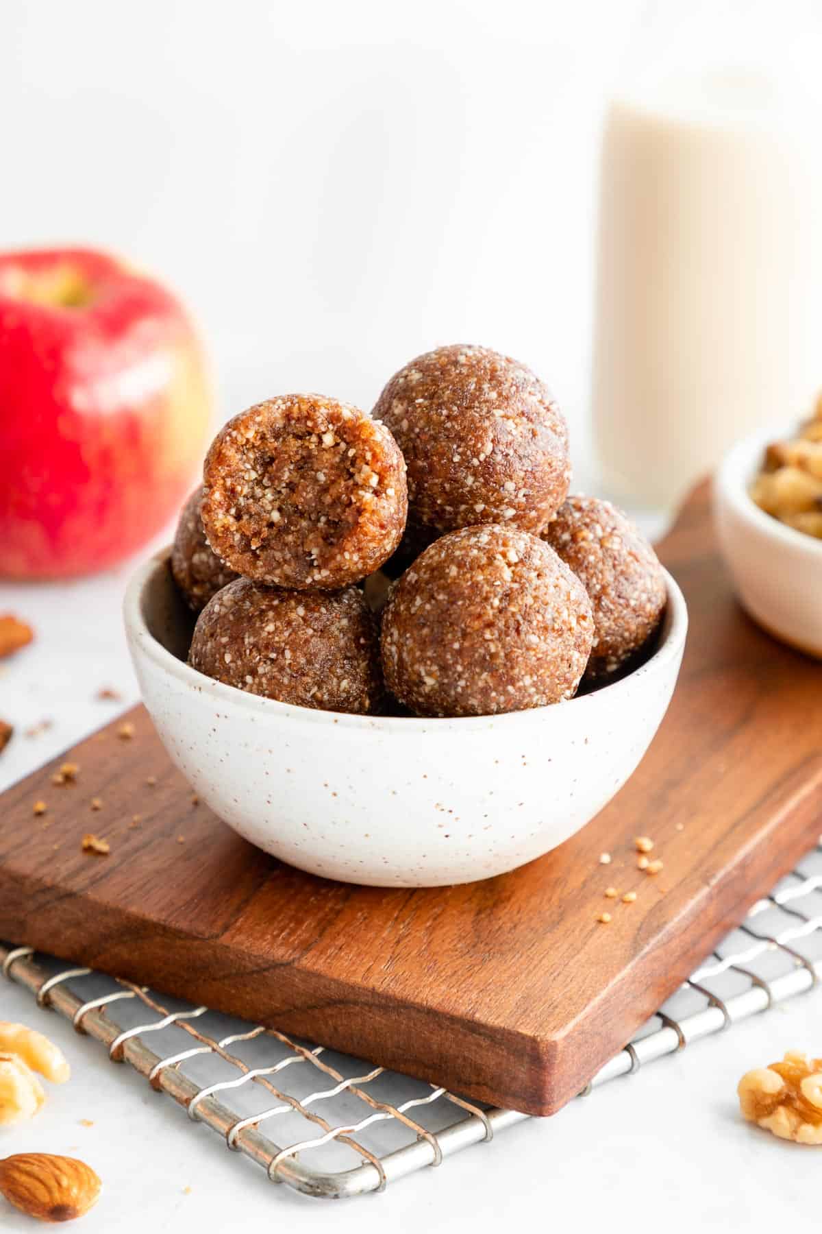 a small ceramic bowl filled with apple pie energy bites with a bite taken out of the middle one