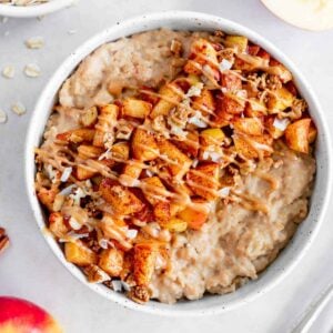 vegan caramel apple oatmeal in a bowl with caramelized apples and healthy caramel sauce on top