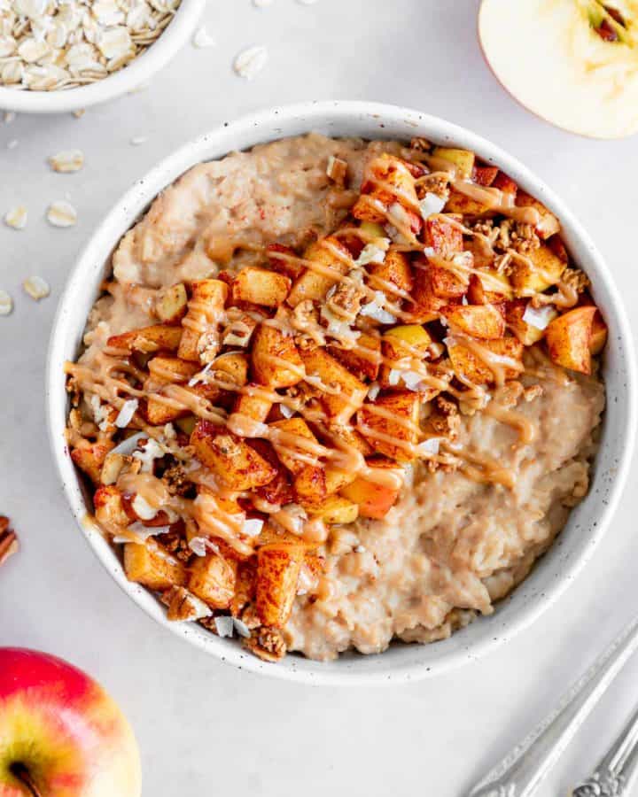 vegan caramel apple oatmeal in a bowl with caramelized apples and healthy caramel sauce on top