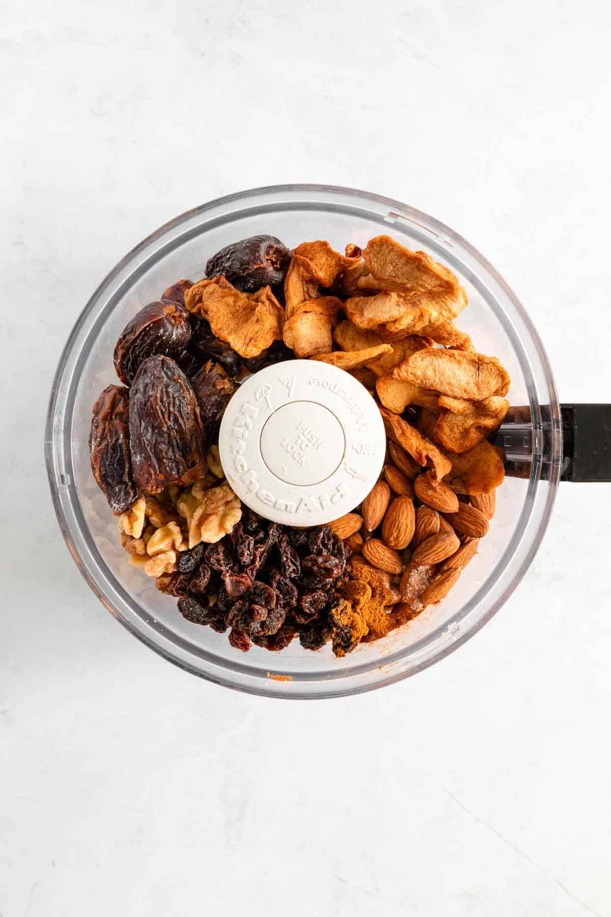 medjool dates, almonds, walnuts, dried apples, and raisins inside a food processor bowl