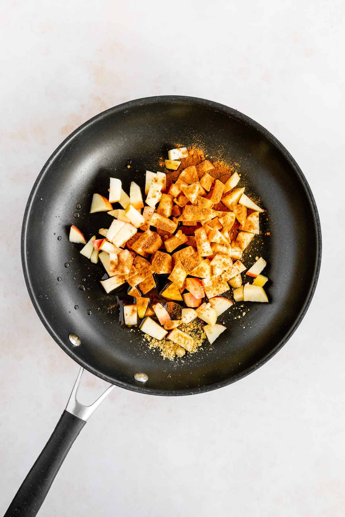 diced apples on a pan with cinnamon, ginger, and nutmeg