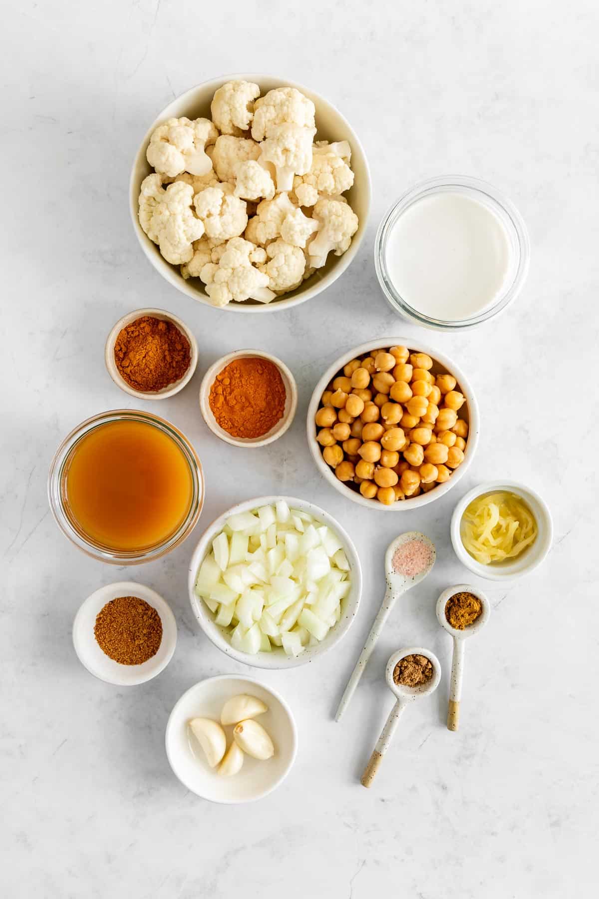 bowls filled with cauliflower, chickpeas, coconut milk, curry powder, onion, garlic, and vegetable broth