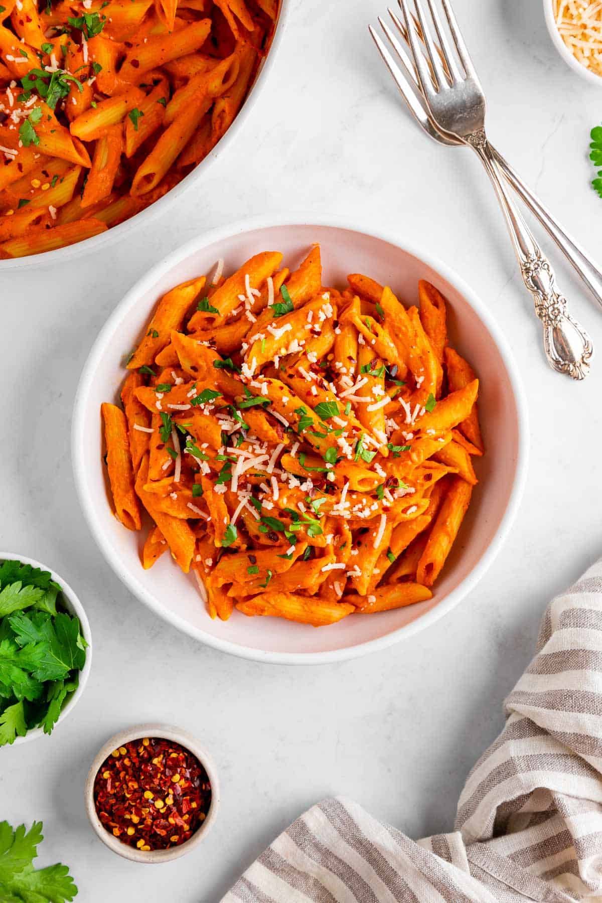a bowl of vegan roasted red pepper pasta with dairy-free parmesan and parsley