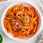 a bowl of vegan roasted red pepper pasta with dairy-free parmesan and parsley