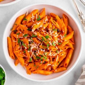 a bowl of vegan roasted red pepper pasta with dairy-free parmesan and parsley