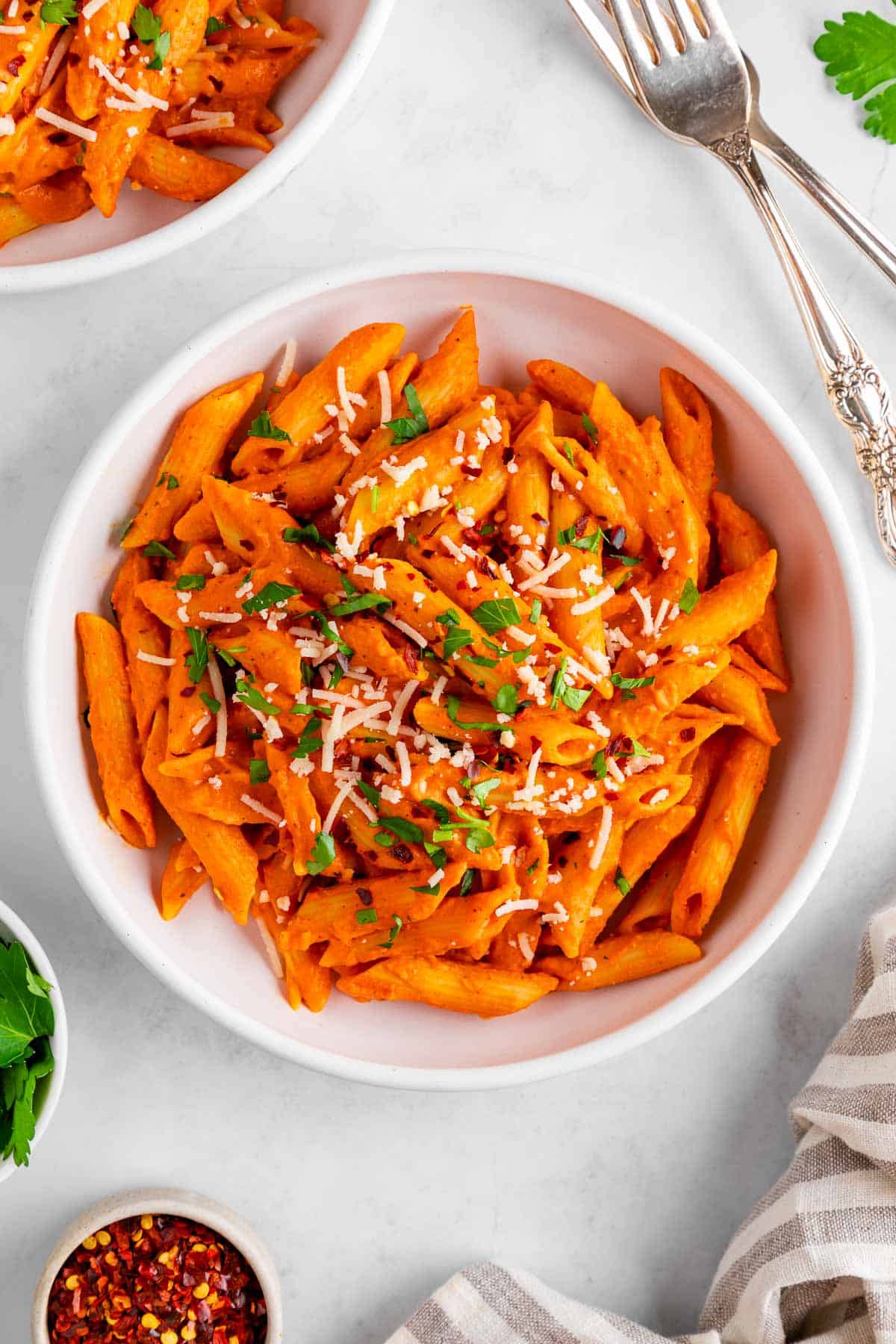 a bowl of vegan roasted red pepper pasta with dairy-free parmesan and parsley