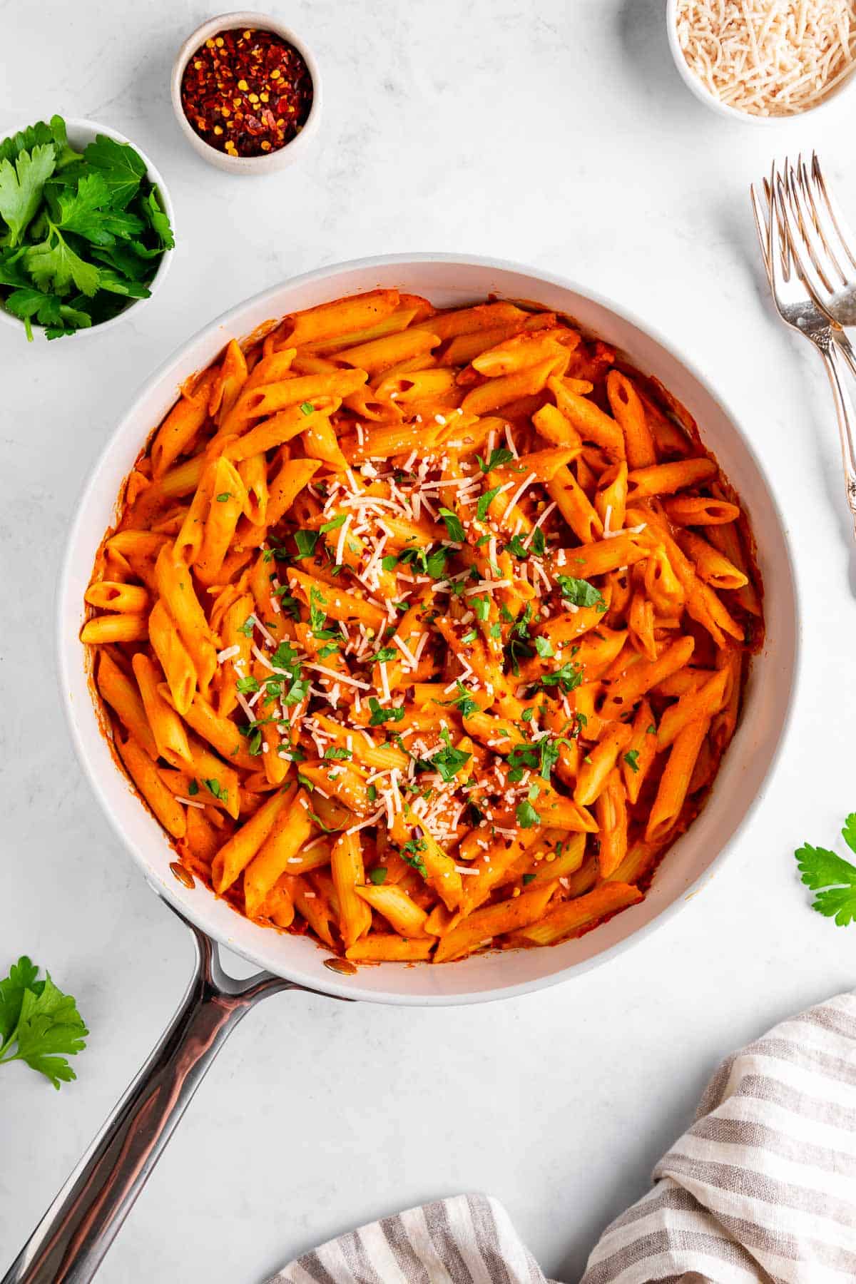 vegan roasted red pepper pasta in a pan with parsley and parmesan