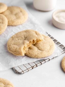 vegan sugar cookies on white parchment paper with a bite taken out of the center cookie