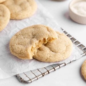 vegan sugar cookies on white parchment paper with a bite taken out of the center cookie