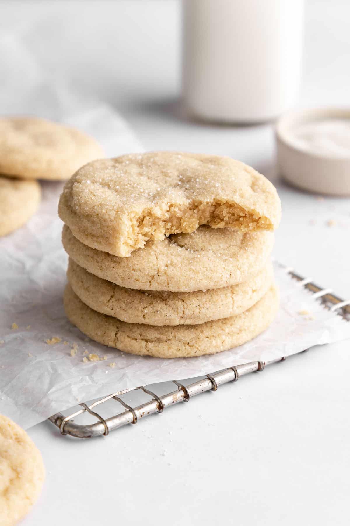 vegan sugar cookies stacked with a bite taken out of the top cookie