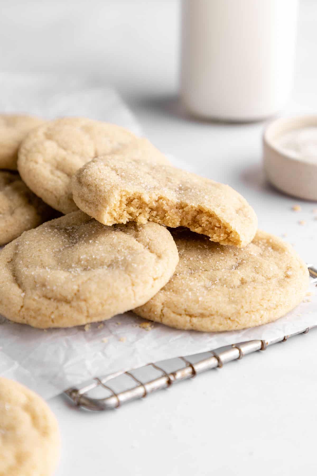 a pile of vegan sugar cookies with a bite taken out of the top cookie