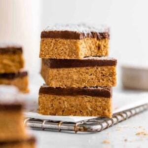 a stack of three no-bake coconut protein bars with a biten taken out of the top one