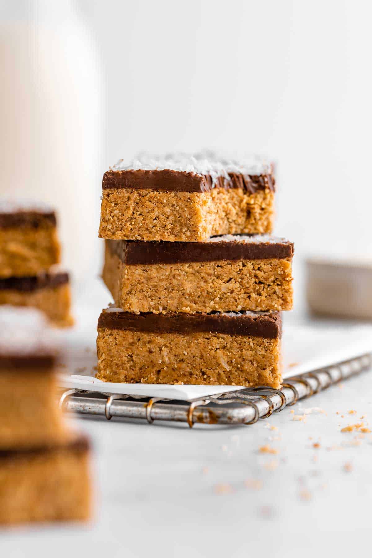 a stack of three no-bake coconut protein bars with a biten taken out of the top one