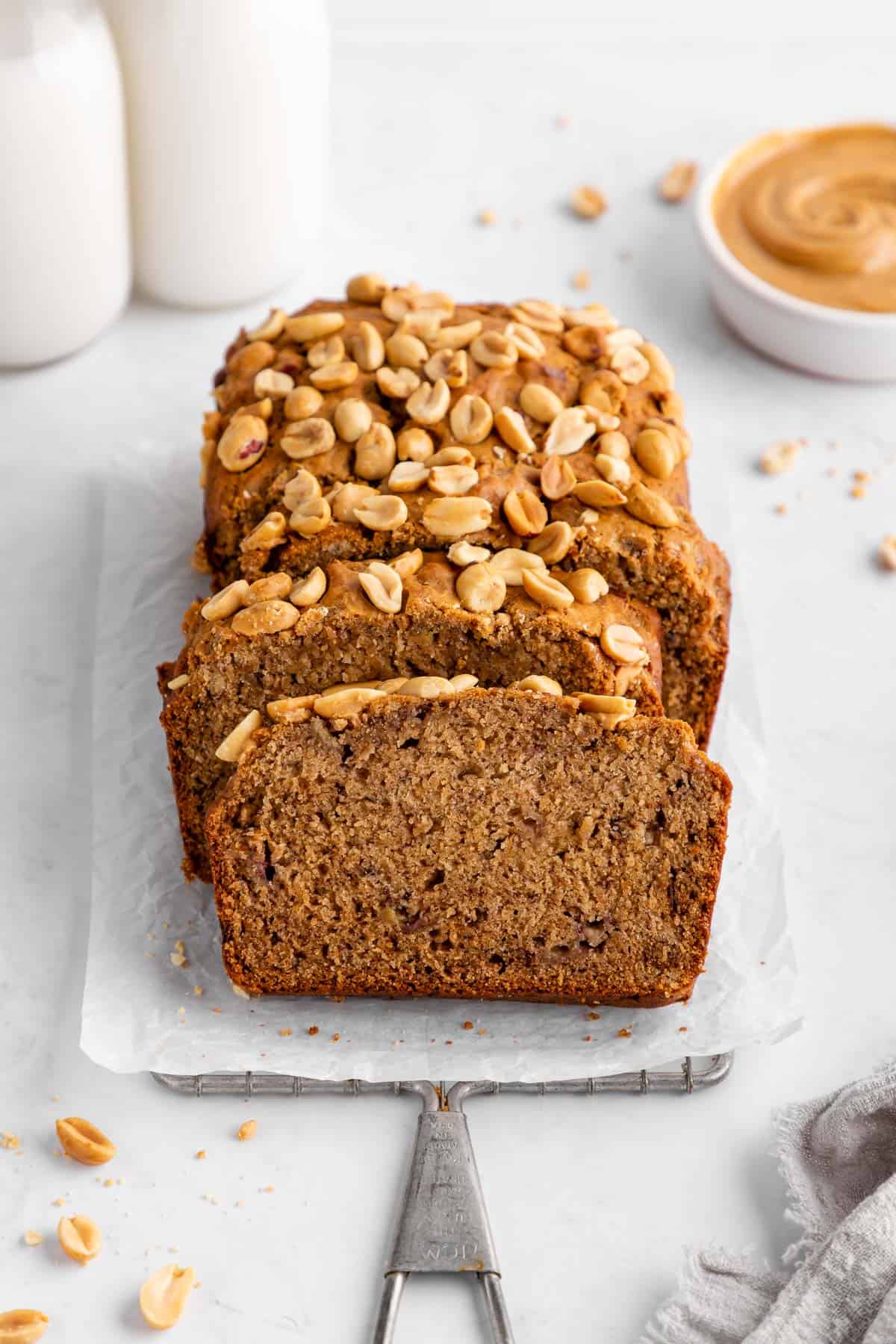 a sliced loaf of vegan peanut butter banana bread on white parchment paper