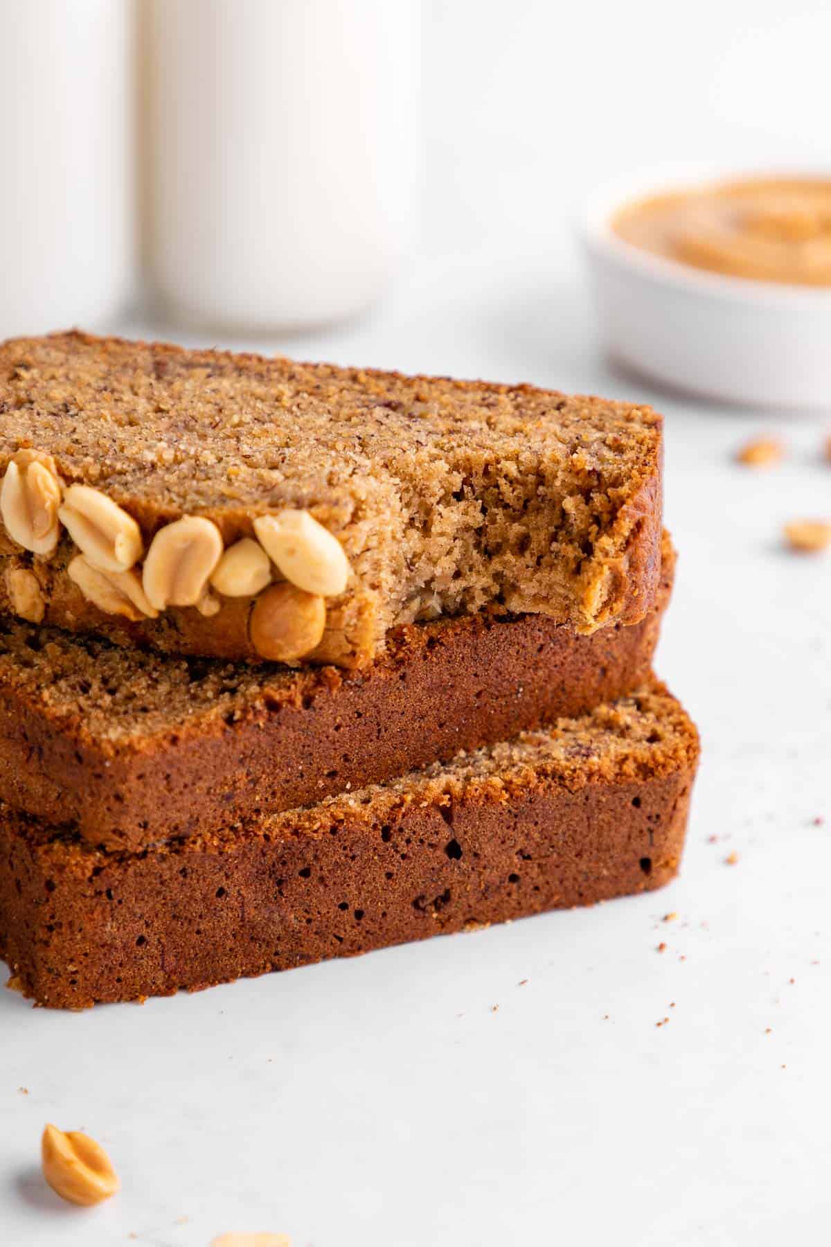 three slices of vegan peanut butter banana bread with a bite taken out of the top slice