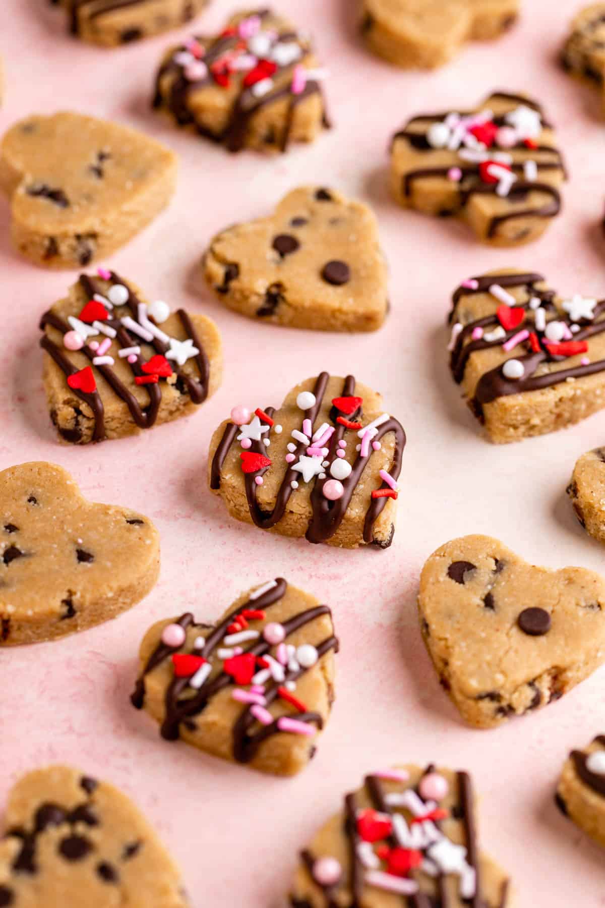 vegan cookie dough hearts with valentine's day sprinkles on a pink surface