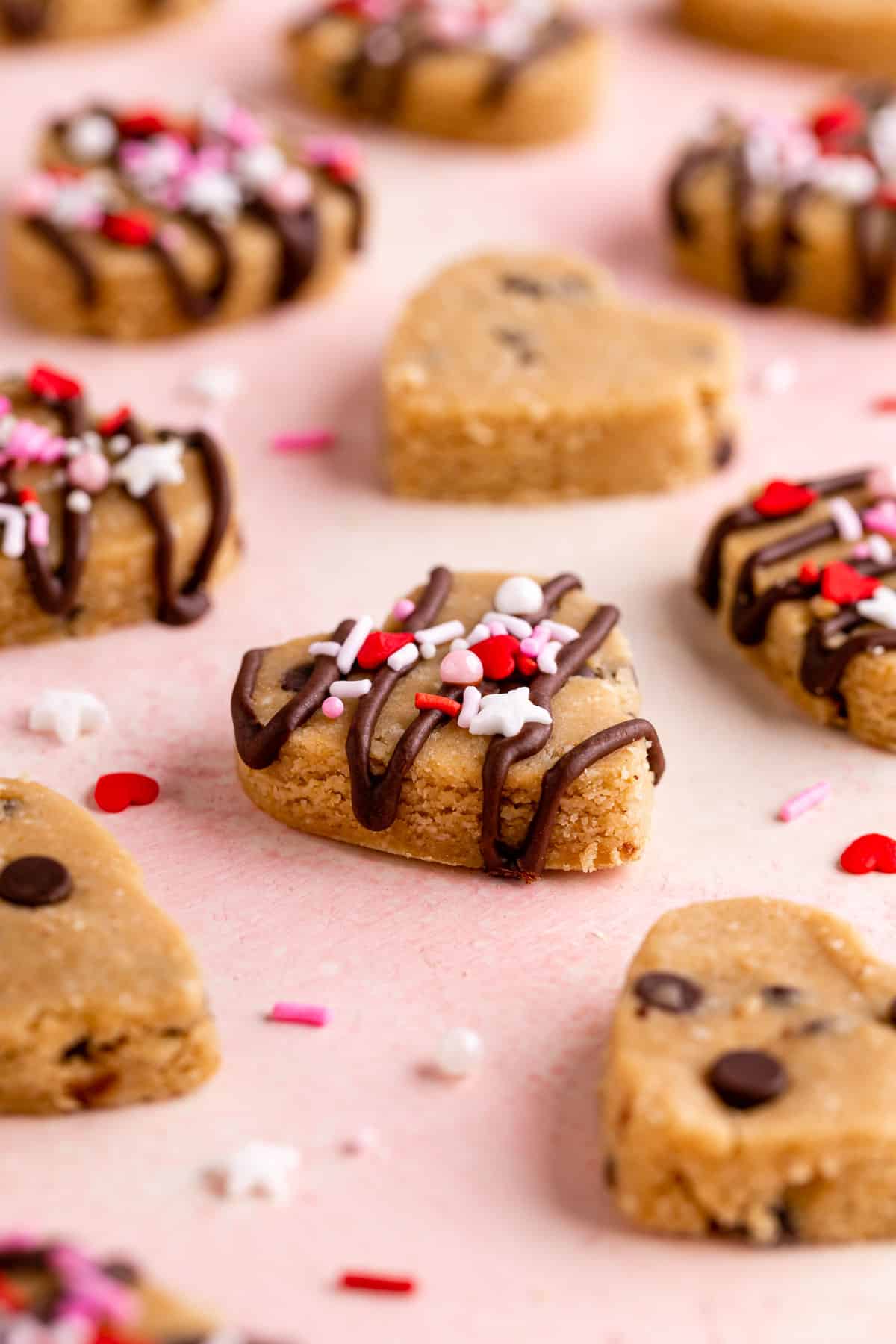 healthy chocolate chip cookie dough hearts with valentine's day sprinkles on a pink surface