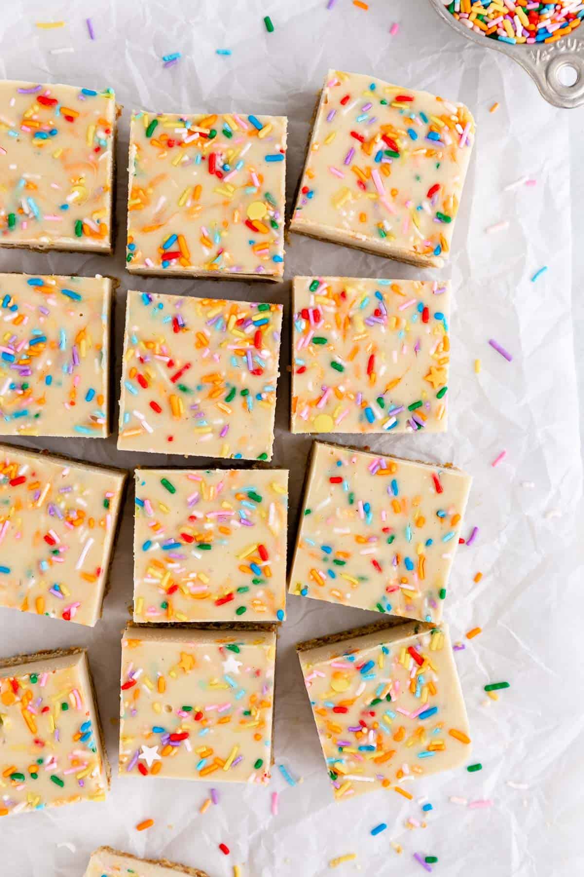 a pile of vegan no-bake funfetti cheesecake bars with rainbow sprinkles