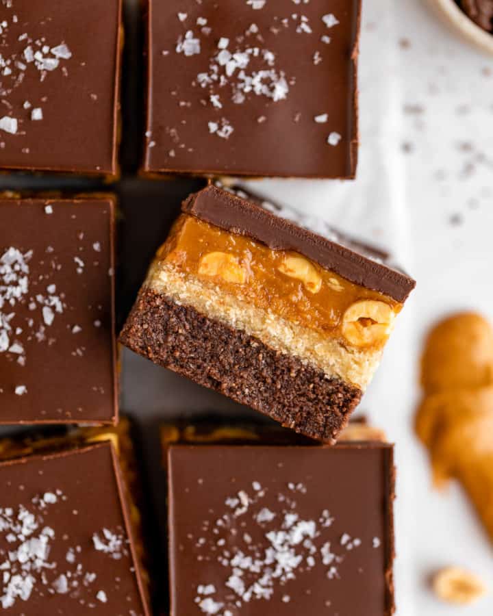 close up photo of no bake snickers brownies with caramel, nougat, peanuts, and chocolate
