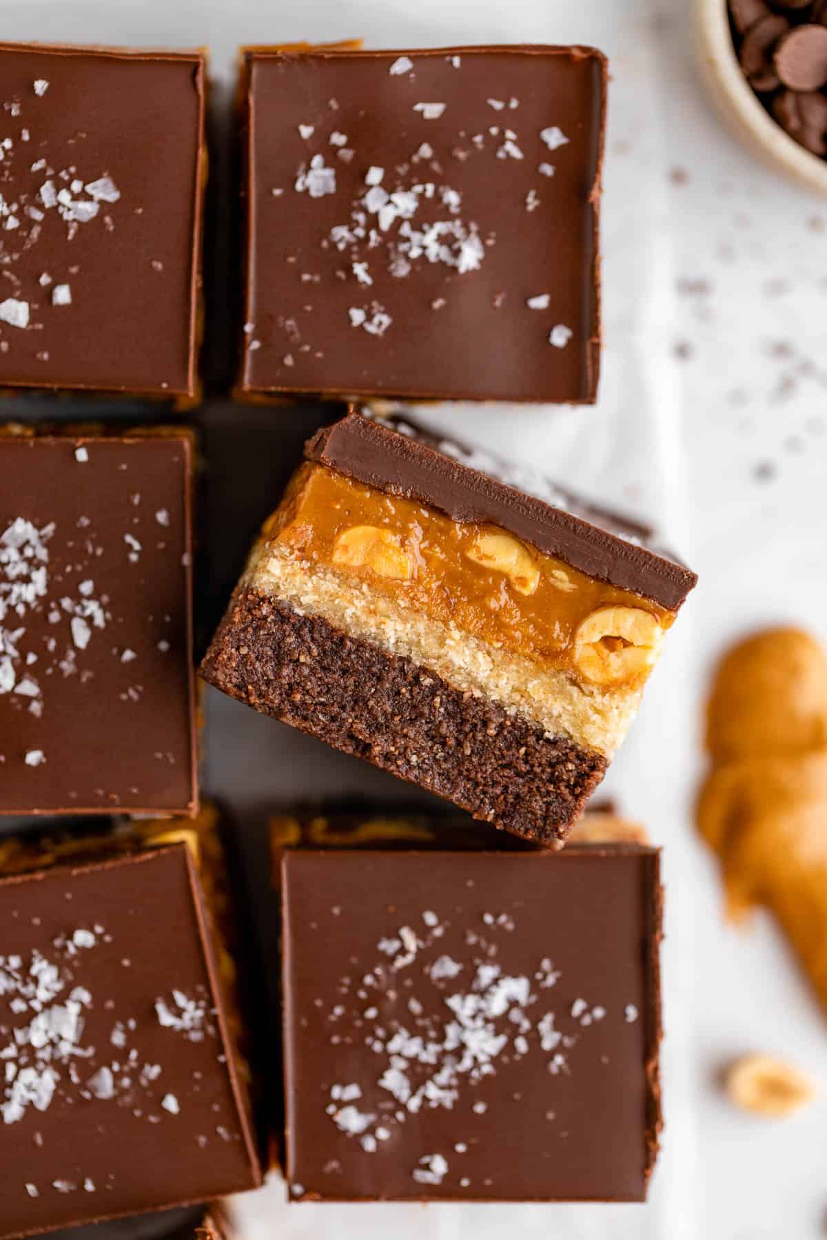 close up photo of no bake snickers brownies with caramel, nougat, peanuts, and chocolate