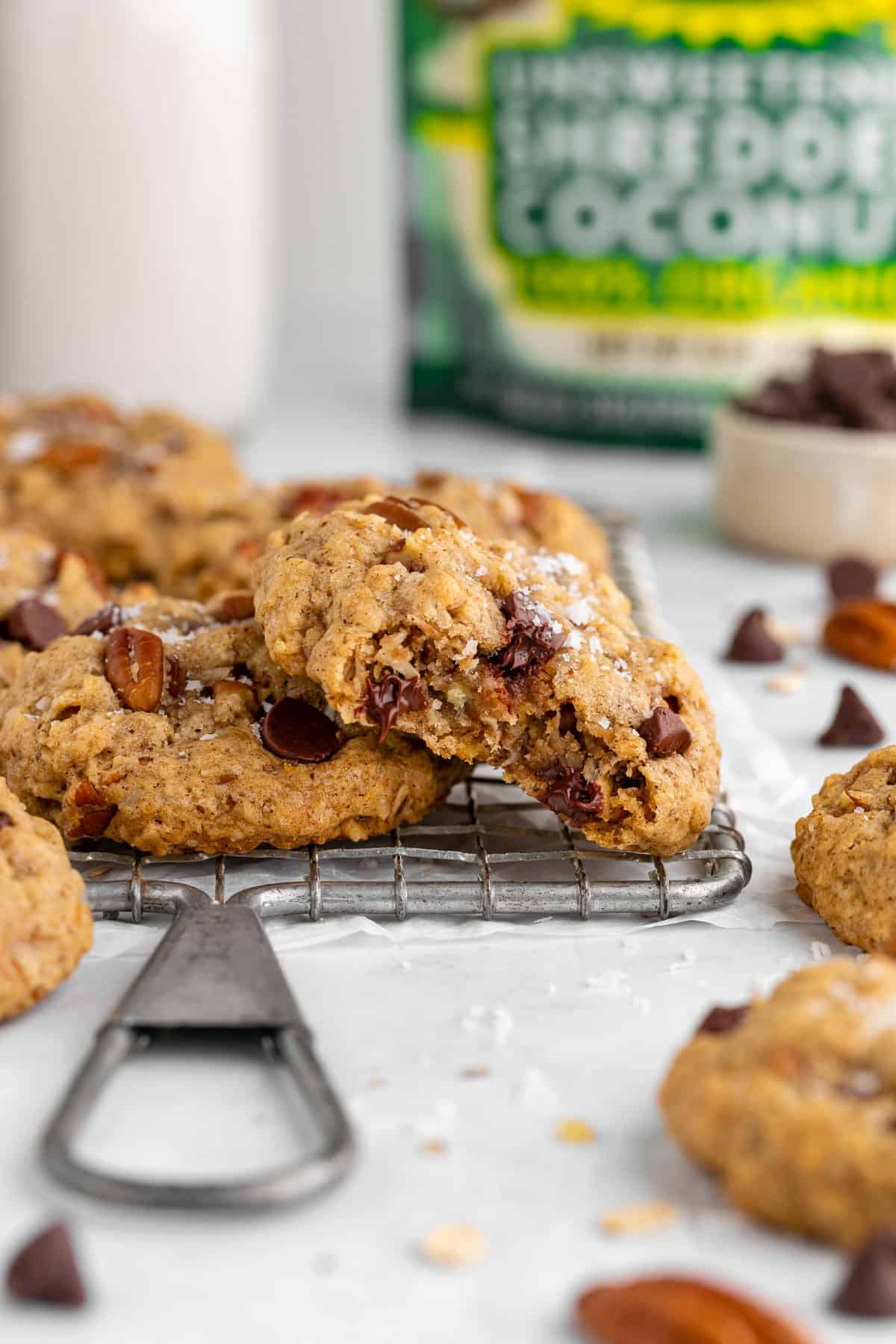 vegan cowboy cookies on a wire cooling rack with a bite taken out of the center one