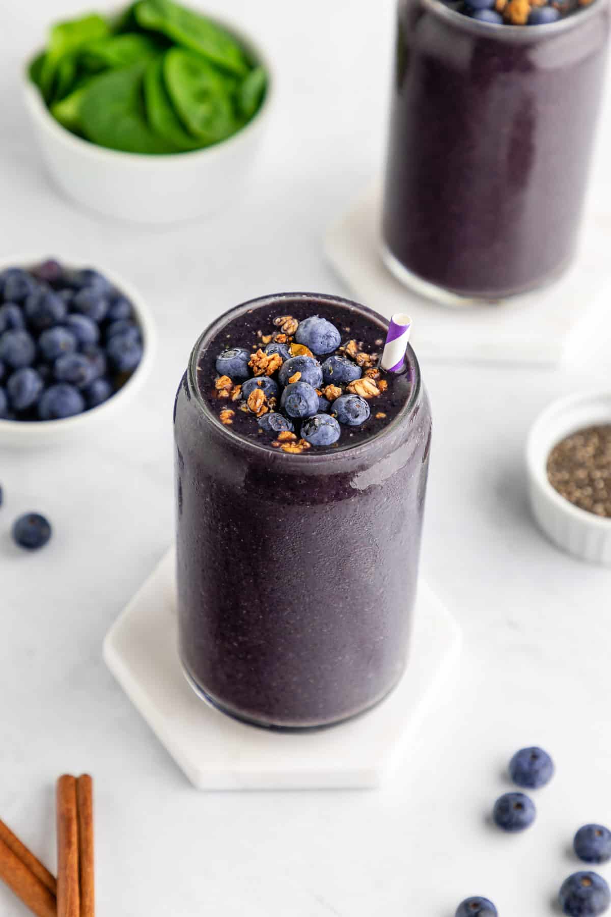 blueberry spinach smoothie in a glass with granola on top