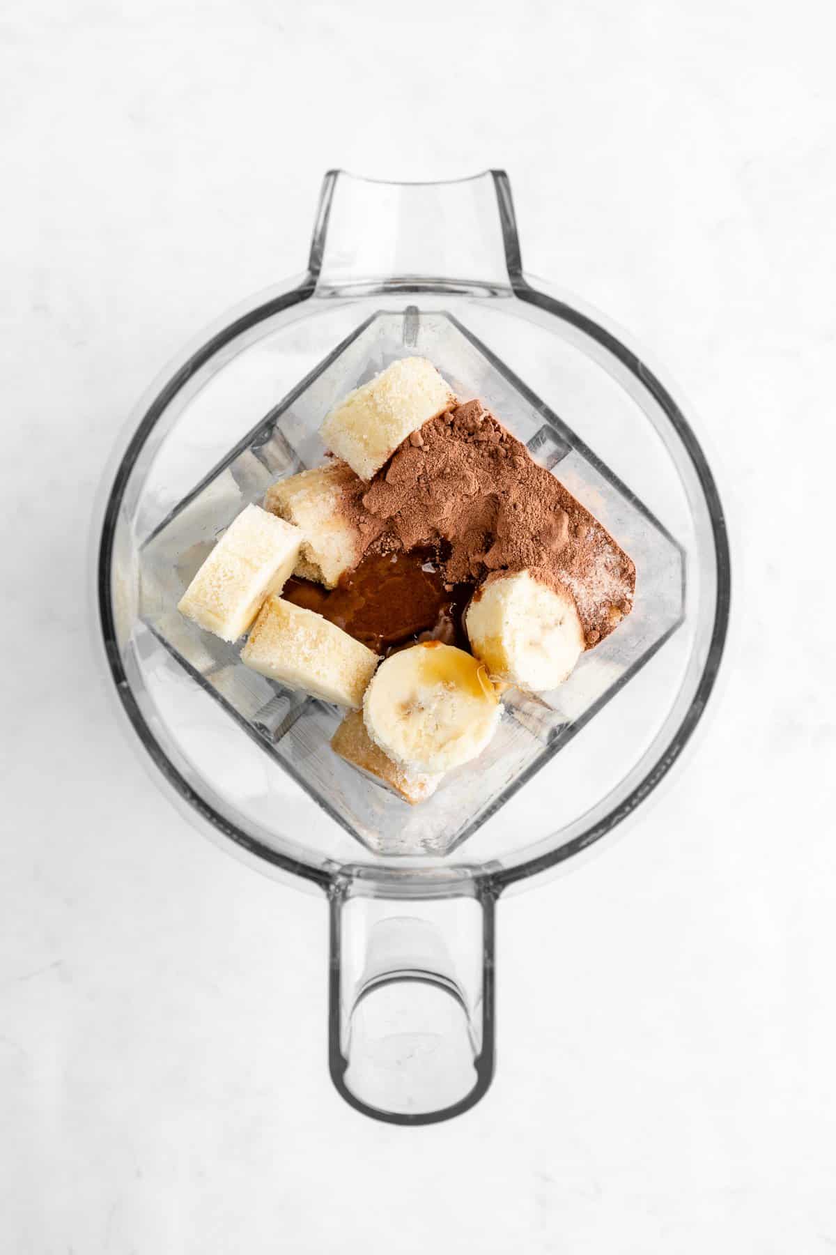 frozen bananas, cacao powder, almond milk, chocolate hazelnut butter, and maple syrup inside a vitamix blender