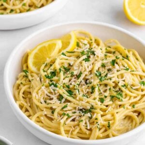 a bowl of creamy vegan lemon pasta with fresh parlsye and vegan parmesan