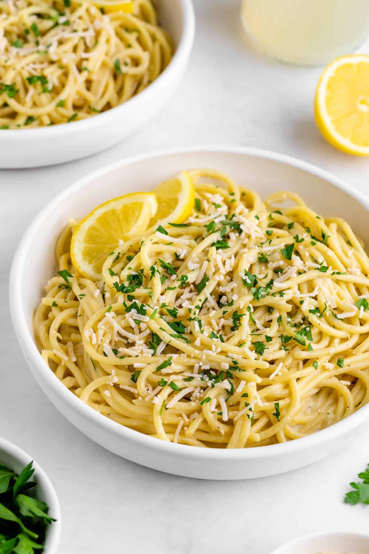 a bowl of creamy vegan lemon pasta with fresh parlsye and vegan parmesan