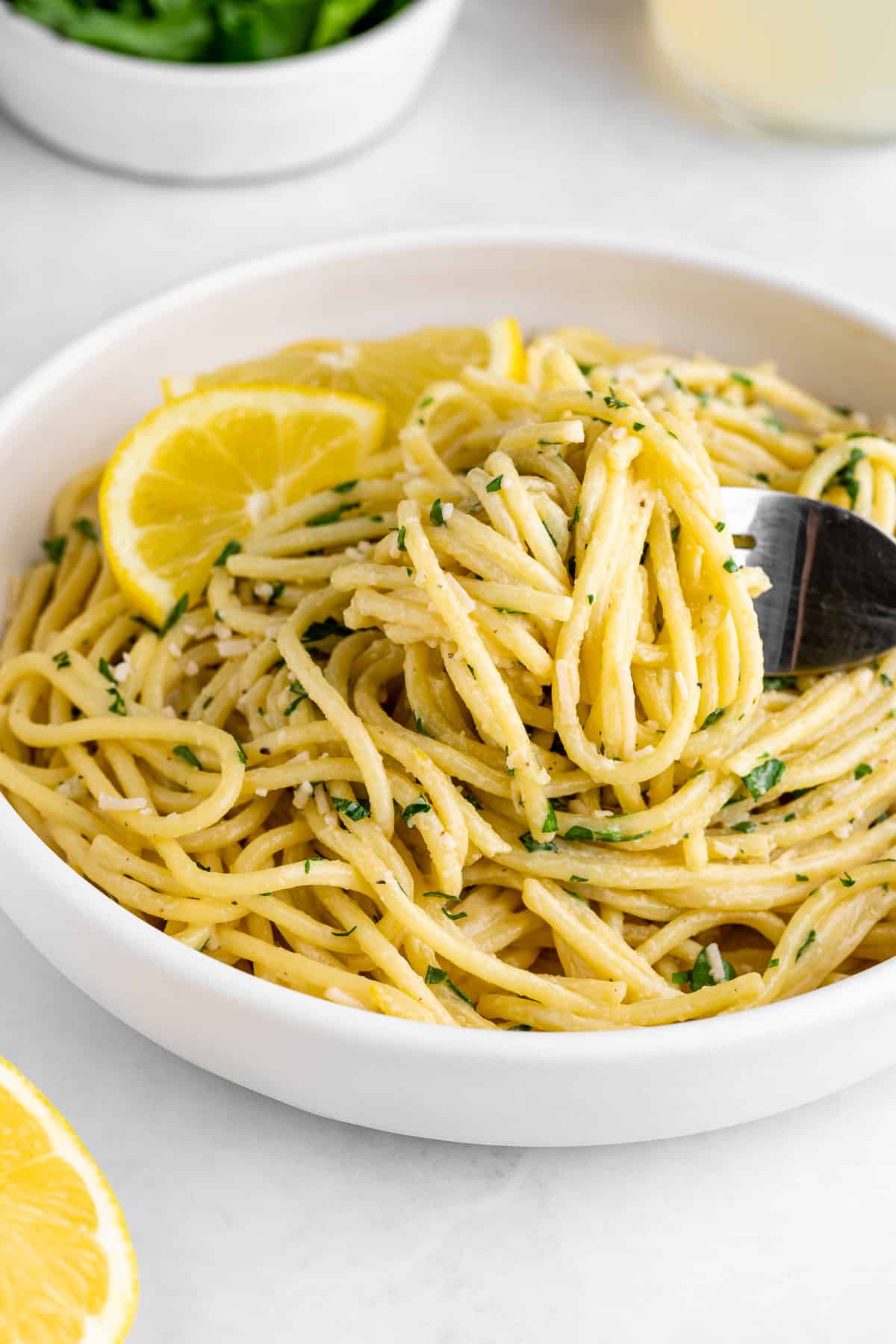 a fork twirling creamy vegan lemon pasta inside a white bowl