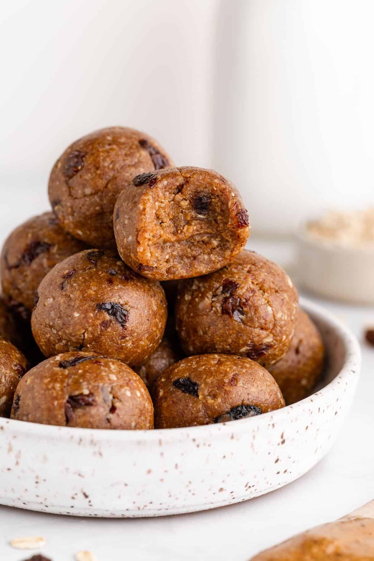 a pile of oatmeal raisin energy bites in a bowl with a bite taken out of one