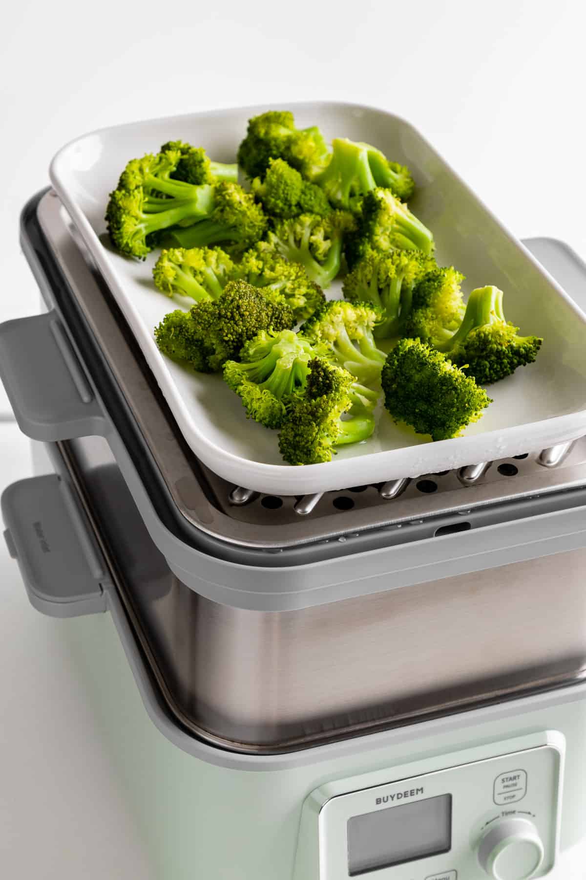 steaming broccoli on the ceramic tray inside the Buydeem two-tier intelligent food steamer