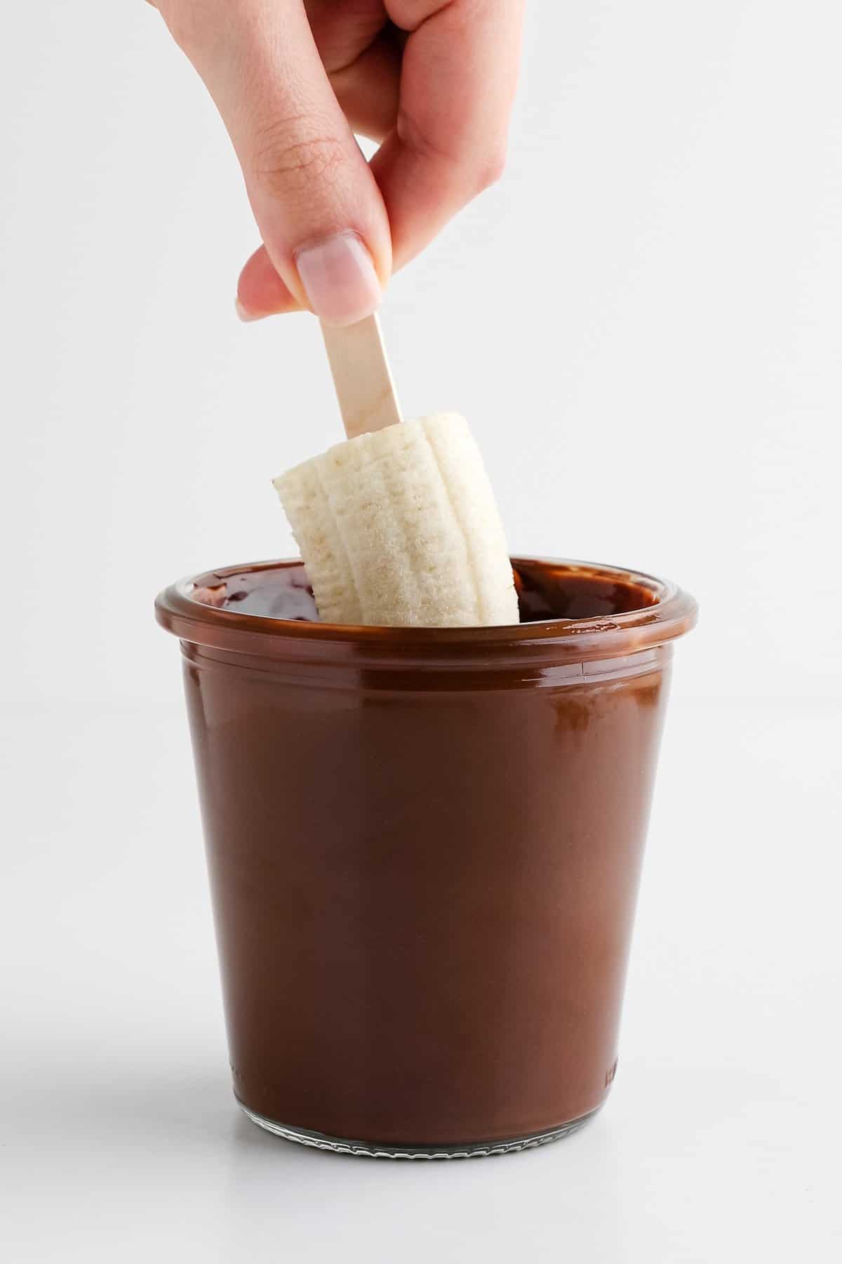 dipped a frozen banana pop into melted chocolate inside a glass weck jar