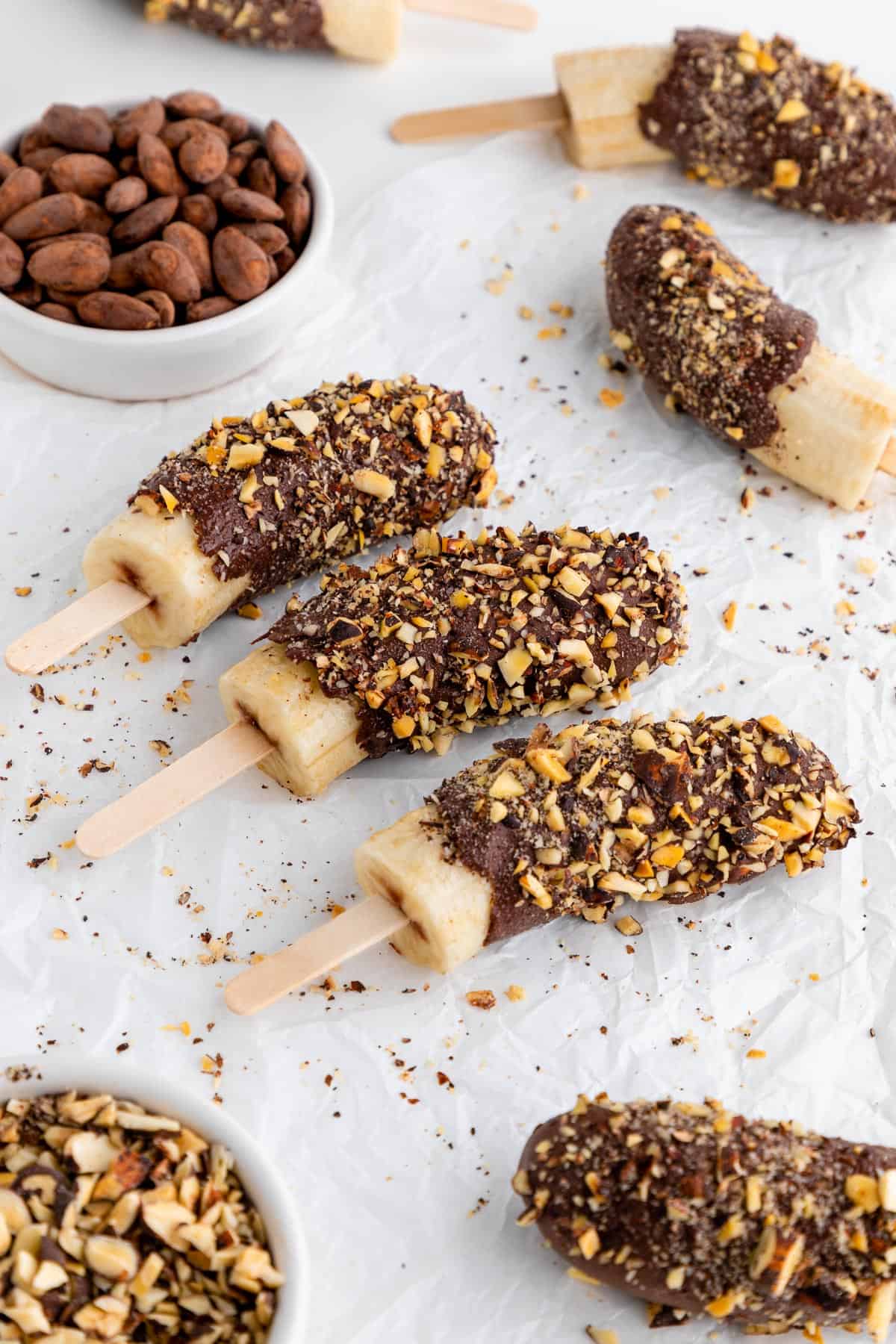 chocolate covered frozen bananas on popsicle sticks with crushed nuts