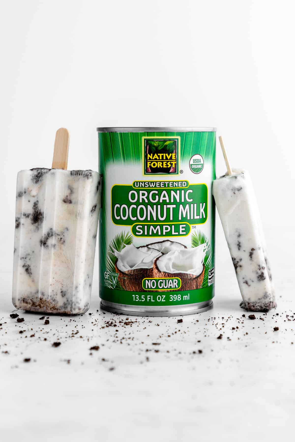 two cookies and cream popsicles resting alongside a can of native forest coconut milk