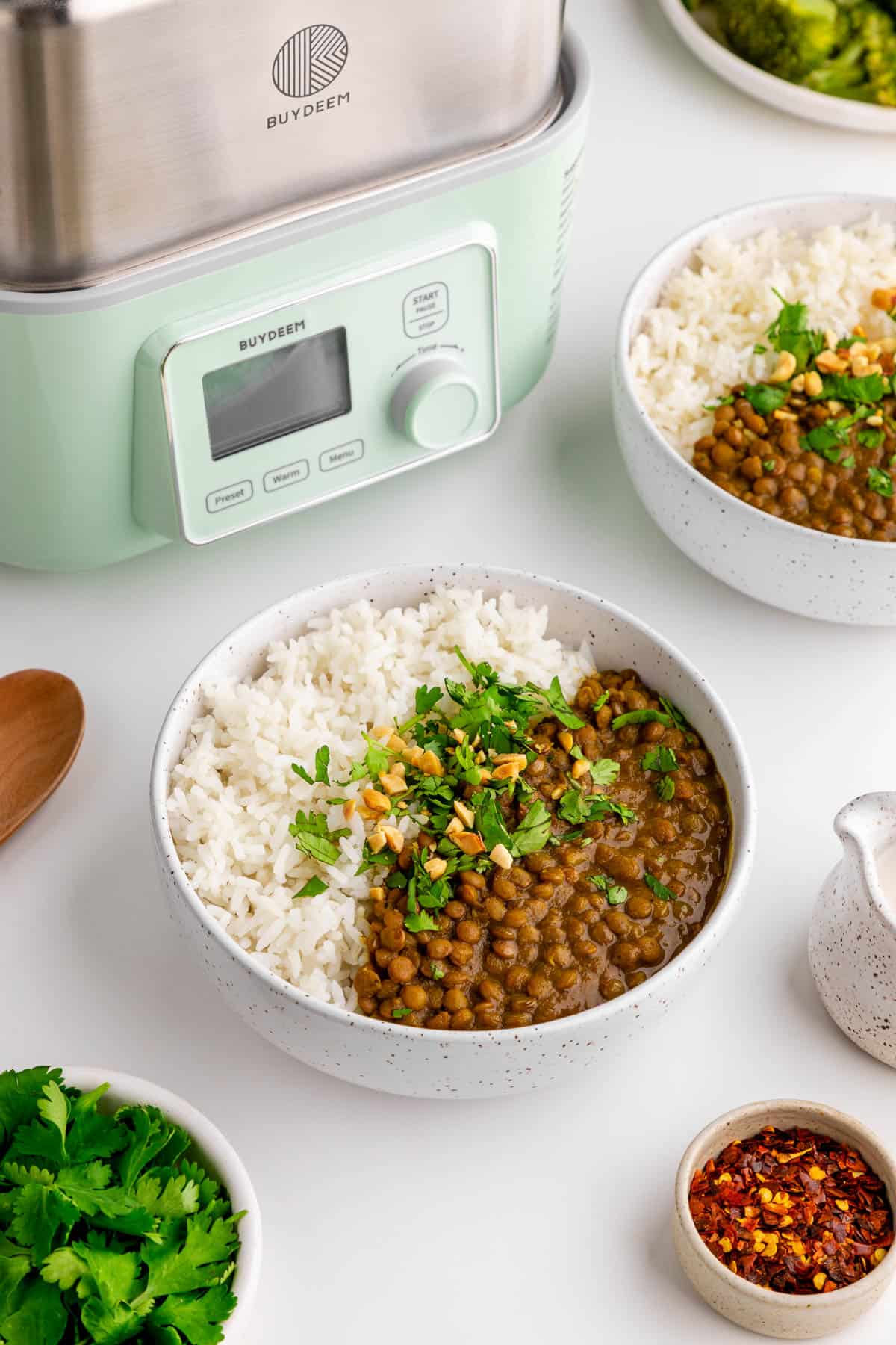 two bowls of slow cooker lentil curry and rice beside the Buydeem two-tier all-in-one intelligent food steamer