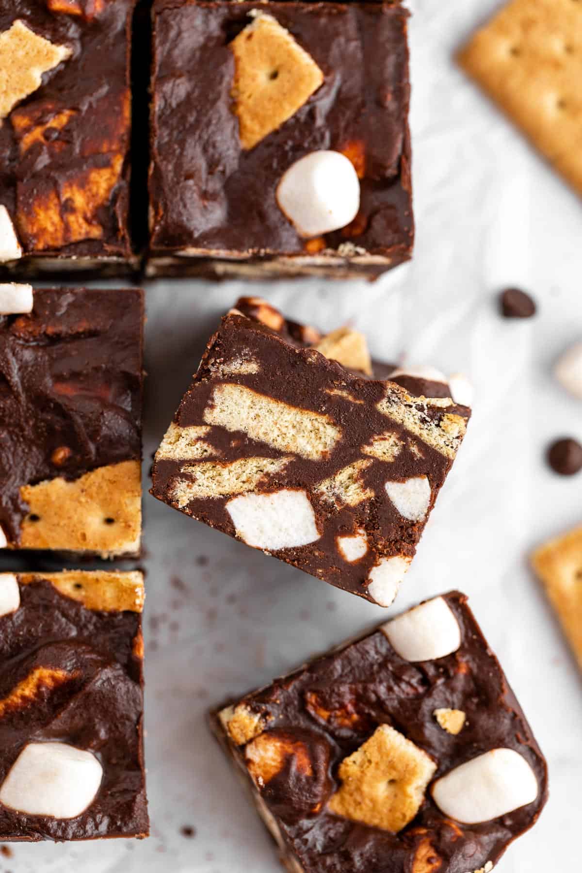 a vegan s'mores fudge bar on its side with chopped graham cracker pieces and mini marshmallows