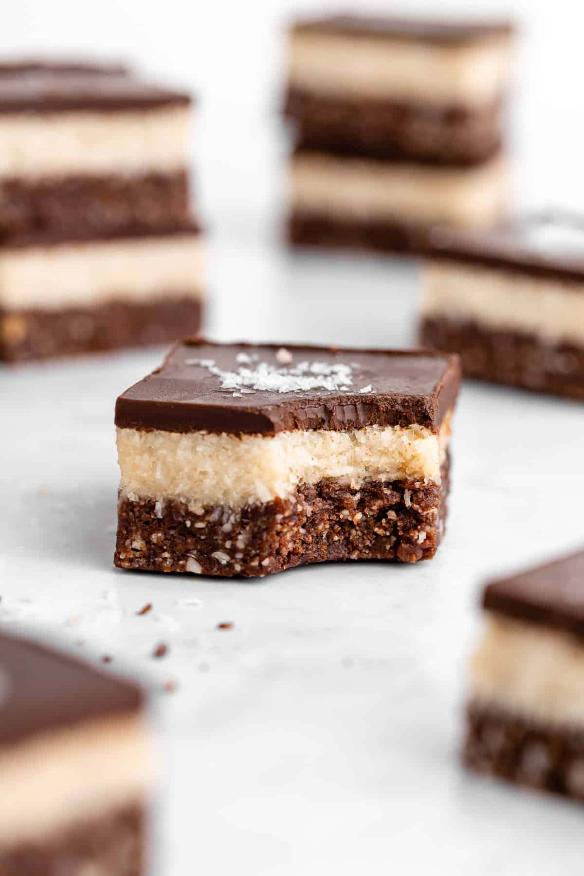a layered no-bake coconut brownie with a bite taken out of it