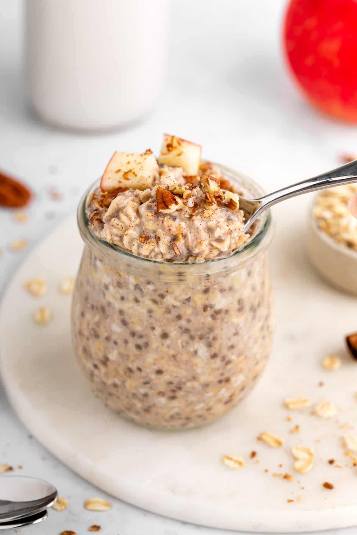 a spoon scooping into vegan apple cinnamon overnight oats inside a glass jar